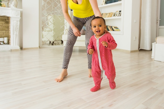 Mignon petit bébé apprenant à marcher, maman tient ses mains.