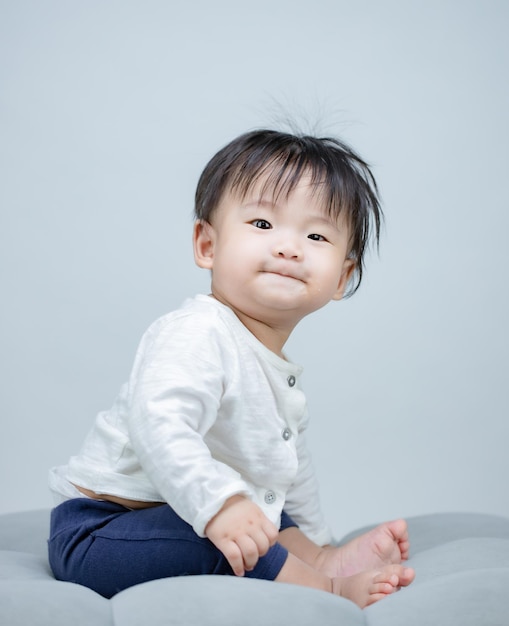 Mignon petit bébé assis sur fond gris