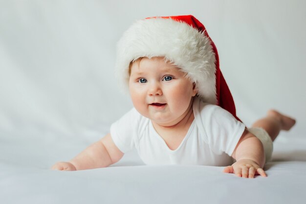 Mignon petit bébé en bonnet de Noel sur blanc.