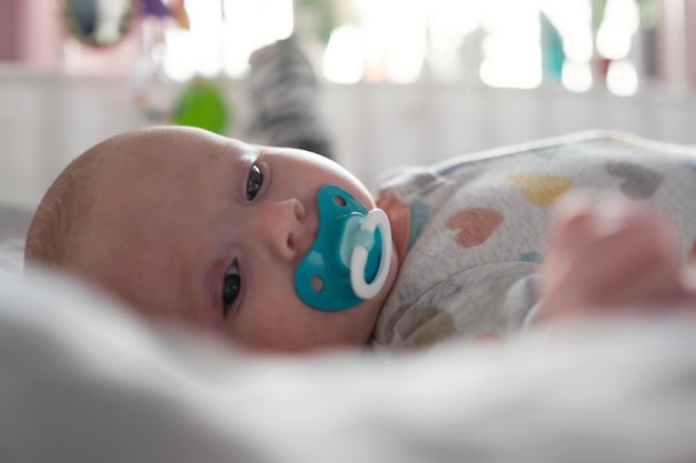 Mignon petit bébé caucasien avec tétine reposant dans son lit