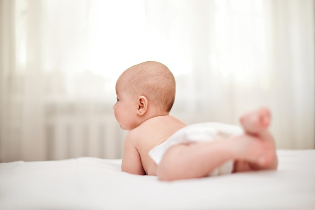 Mignon petit bébé en couche sur le lit