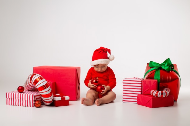 Mignon petit bébé dans un costume de père Noël avec des cadeaux