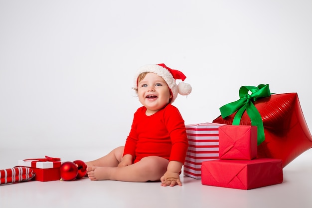 Mignon petit bébé dans un costume de père Noël avec des cadeaux