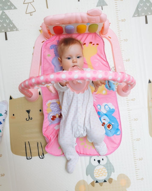 Un mignon petit bébé est assis sur un tapis parmi des jouets colorés un enfant joue avec un jouet