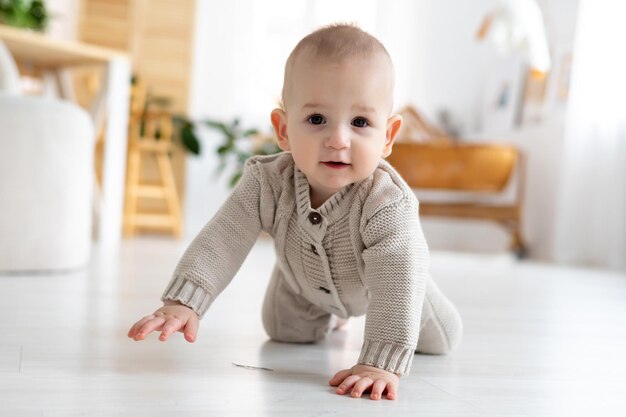 Mignon Petit Bébé Garçon Dans Un Costume Tricoté En Laine Apprenant à  S'asseoir Sur Le Sol Dans Un Salon Lumineux Bébé Souriant Jouant Au  Développement Précoce Des Enfants