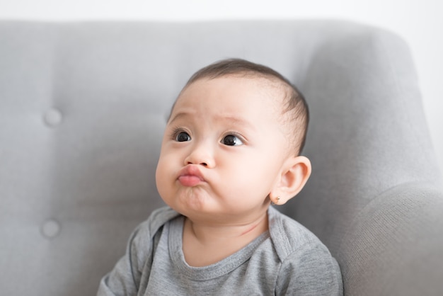 Mignon petit bébé jouant à la maison dans une pièce grise