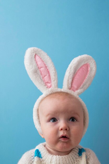 Mignon petit bébé portant des oreilles de lapin de Pâques blanc sur fond bleu