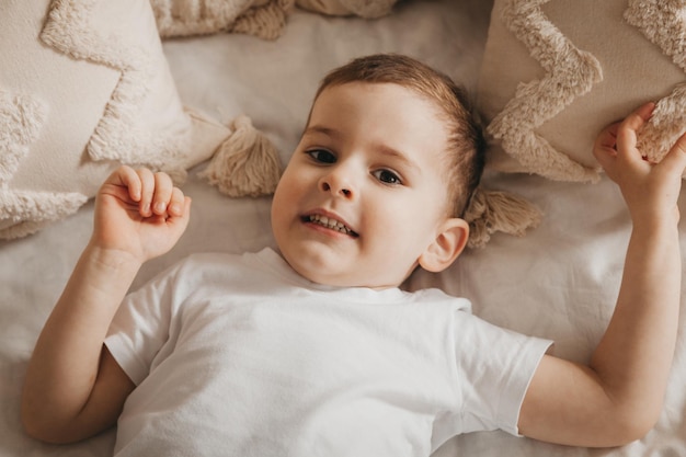 Mignon petit bébé se trouve sur le lit vue de dessus portrait d'un garçon au lit