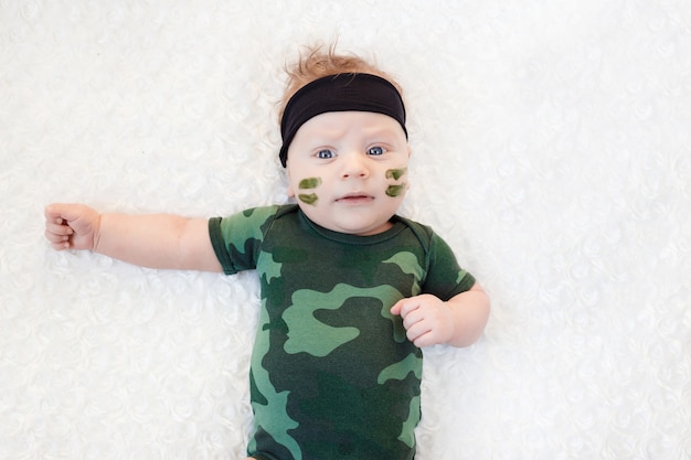 Mignon petit bébé soldat en uniforme. petit garçon en costume de camouflage sur fond blanc