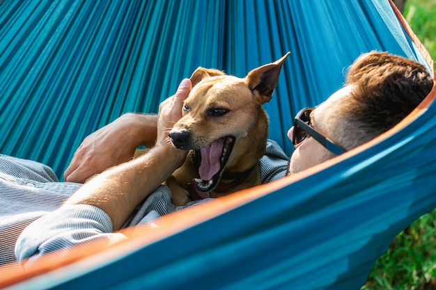 Un mignon petit chien est en train de bâiller. Un chien se repose avec son propriétaire dans un hameau par un jour d'été ensoleillé.