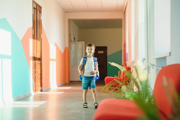 Mignon petit écolier assis sur le couloir de l'école