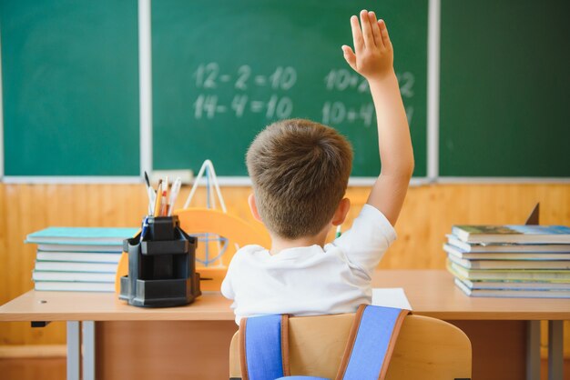 Mignon petit écolier assis dans la salle de classe