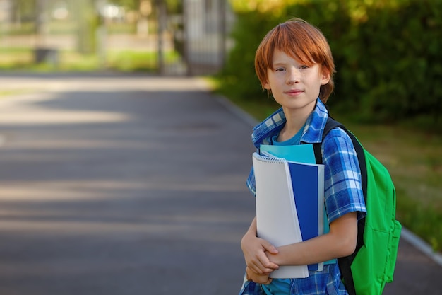 Photo mignon petit écolier avec son sac à dos à l'extérieur sur le chemin de l'école le jour d'automne ensoleillé