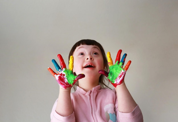 Mignon petit enfant aux mains peintes. Isolé sur fond gris.