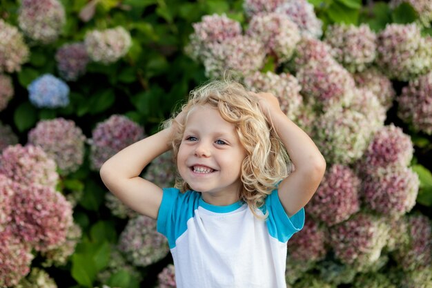 Mignon petit enfant avec beaucoup de fleurs dans le jardin