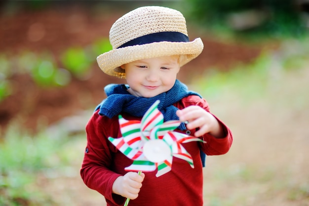 Mignon petit enfant tenant le moulin à vent jouet. Heureux bambin garçon tenant le drapeau italien à l&#39;extérieur