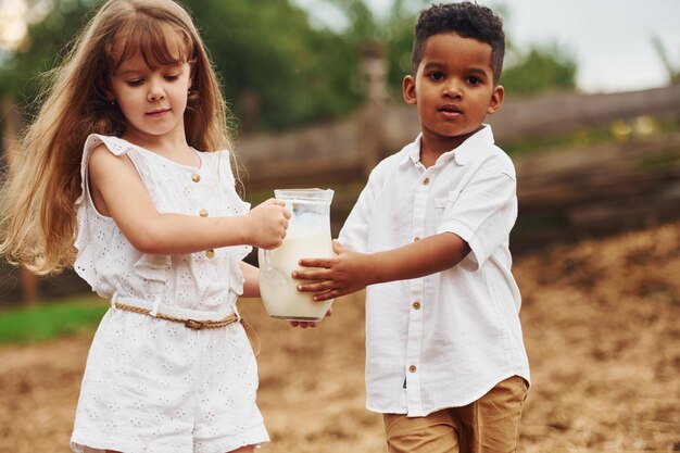 Mignon petit garçon afro-américain avec une fille européenne est à la ferme avec du lait