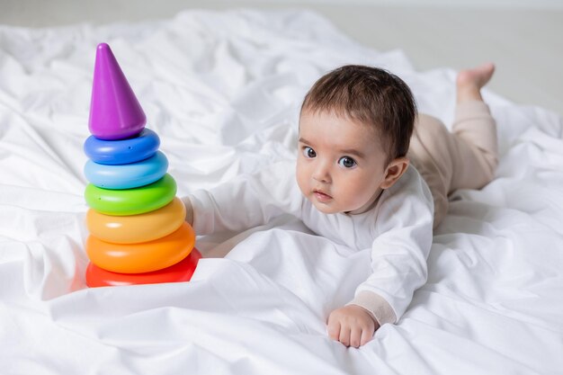 mignon petit garçon allongé sur une couverture et jouant avec la santé de bannière de carte jouet pyramide colorée