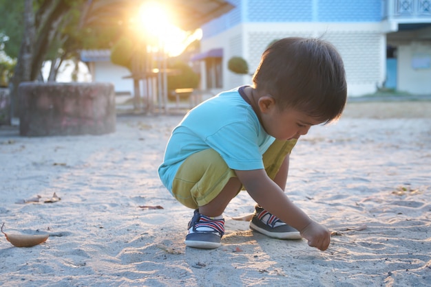 Photo mignon petit garçon asiatique jouant du sable dans le parc