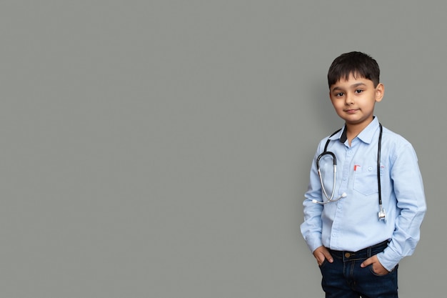 Mignon petit garçon asiatique pakistanais porter une chemise blanche avec un stéthoscope jouant au docteur, heureux petit enfant d'âge préscolaire métis faisant semblant de pediatri