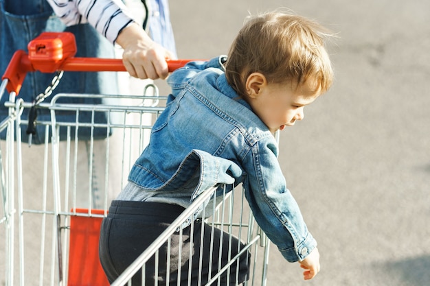 Mignon petit garçon assis dans un caddie