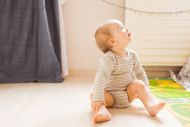 Mignon petit garçon assis sur le sol dans la chambre