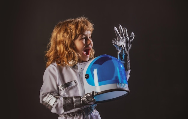 Mignon petit garçon astronaute enfant en combinaison spatiale tenant un casque sur fond noir enfant dans un astronau