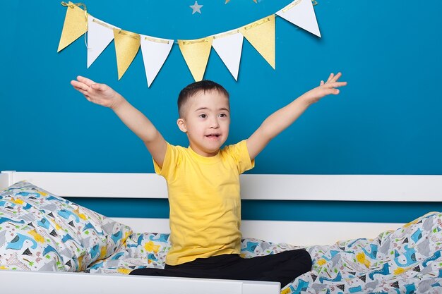 Mignon petit garçon atteint du syndrome de Down sur le lit dans la chambre à coucher