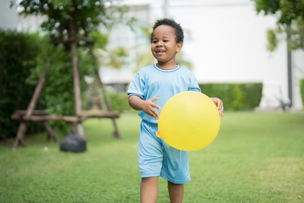 Mignon petit garçon avec des ballons dans le parc par temps clair