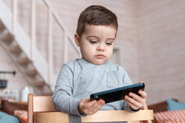 Mignon petit garçon en bas âge jouant avec un smartphone en bonne santé, un bébé touchant un téléphone portable avec des doigts.