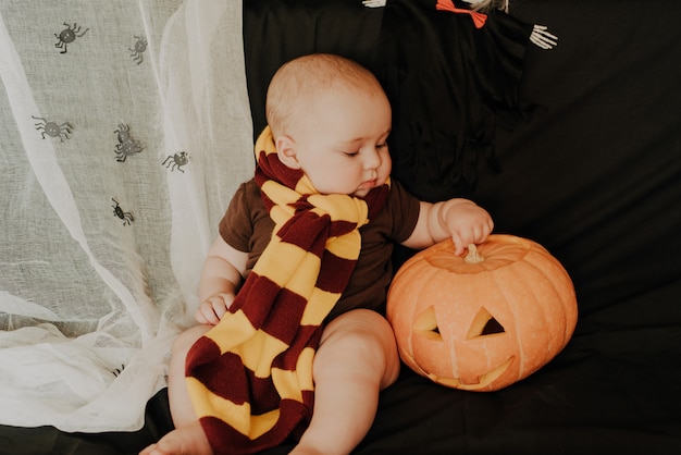 Mignon petit garçon bébé caucasien assis et jouant avec la citrouille Jack