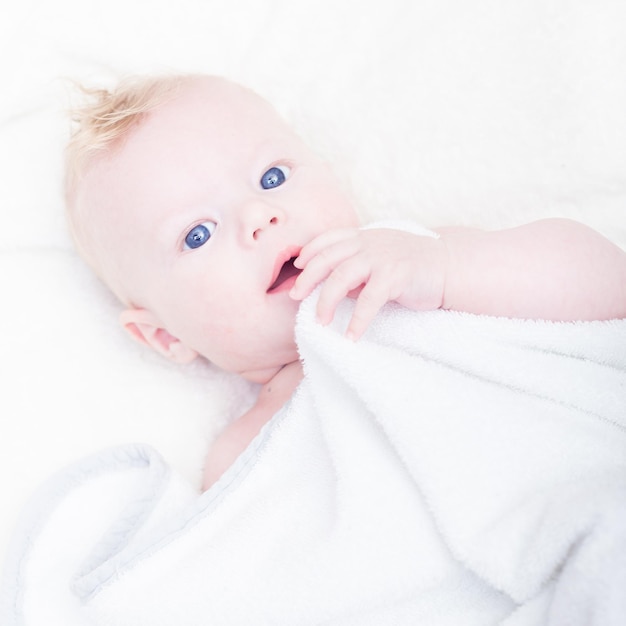 Mignon petit garçon blond aux yeux bleus avec son ours en peluche et son éléphant préférés.