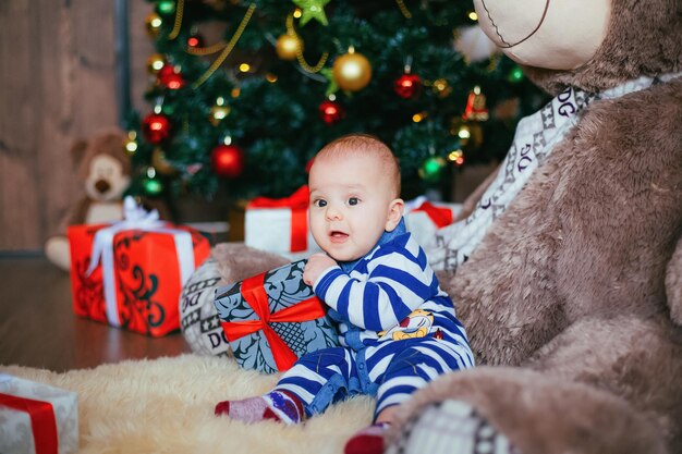 Mignon Petit Garçon Avec Boîte-cadeau Dans Les Mains Portant Sur L'ours En Peluche Fury Enfant Dans La Décoration Du Nouvel An