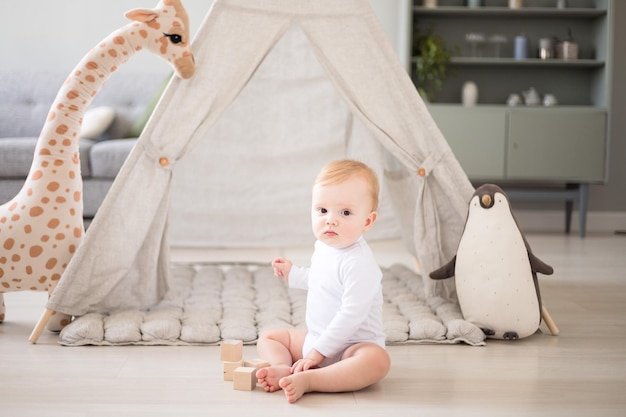 Un mignon petit garçon en bonne santé dans une chambre d'enfant spacieuse et lumineuse à la maison avec un wigwam peluches textiles pour enfants Un enfant joue dans le salon de la maison