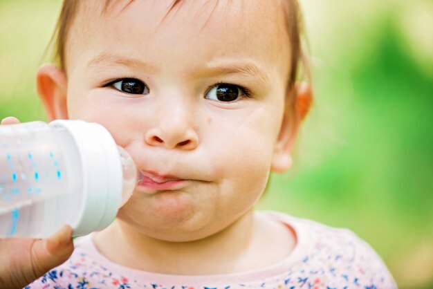 Mignon petit garçon buvant au froid de la bouteille claire dans la chaude journée ensoleillée en été