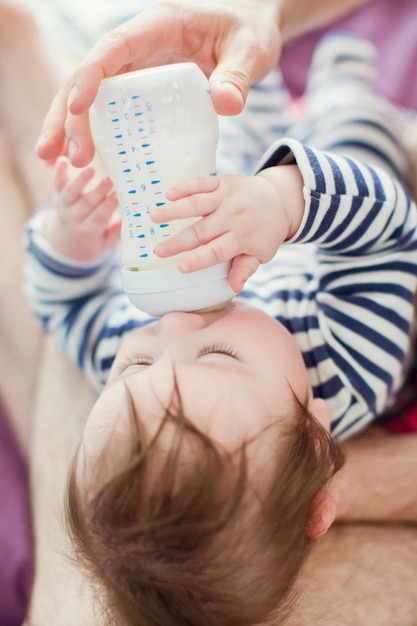 Mignon petit garçon buvant du lait dans une bouteille en plastique