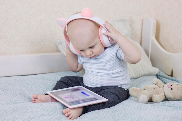 Mignon petit garçon avec casque et tablette numérique Adorable enfant en bas âge assis sur un canapé et écouter de la musique
