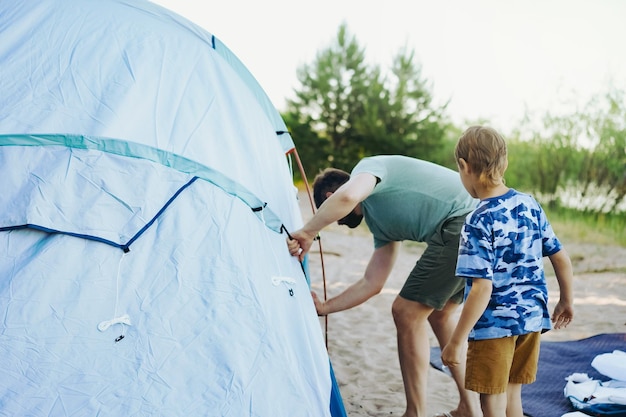 Mignon petit garçon caucasien aidant à monter une tente Concept de camping familial