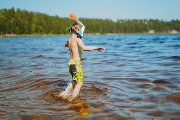 Mignon petit garçon caucasien portant un masque de plongée en apnée va nager dans la mer