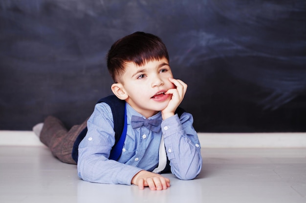 Mignon petit garçon en chemise bleue rêvant à la maison