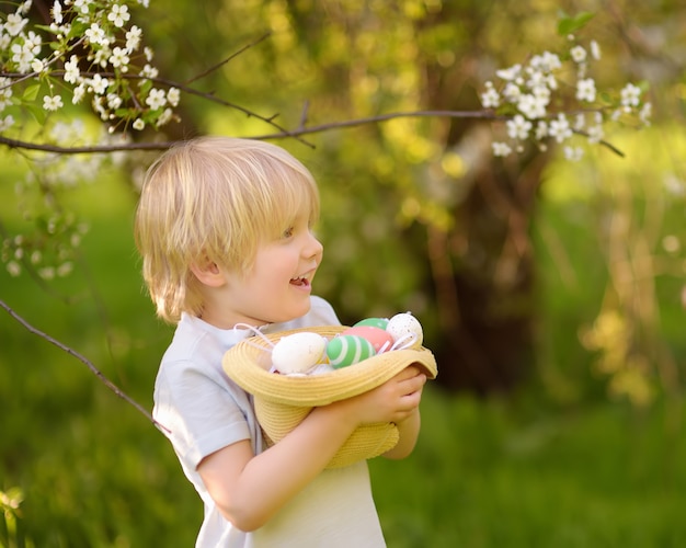 Un mignon petit garçon cherche l'oeuf de Pâques dans le parc du printemps.