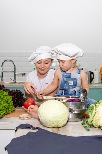 Un mignon petit garçon en costume de chef cuisine des aliments avec des émotions