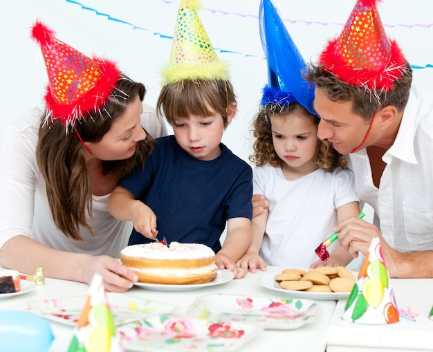 Mignon petit garçon coupe un gâteau d&#39;anniversaire pour sa famille