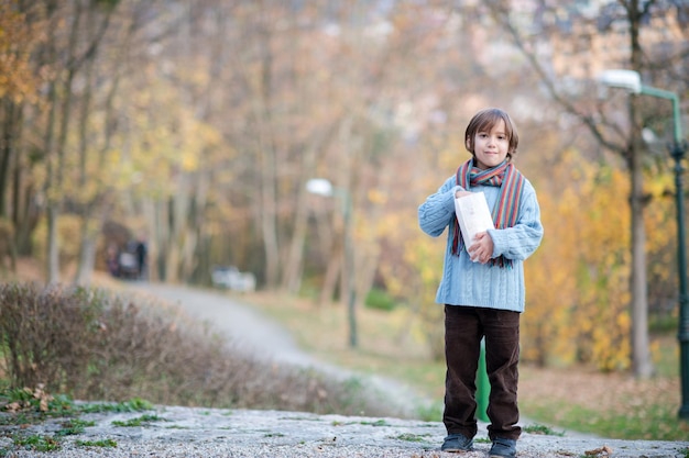 mignon petit garçon dans le parc mangeant du pop-corn en automne jour nuageux