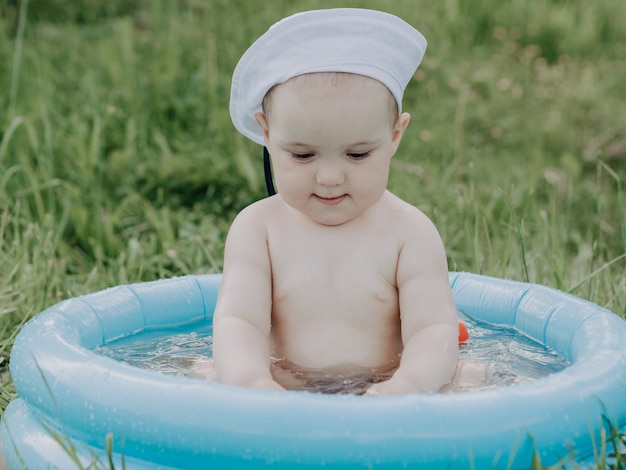 Mignon petit garçon dans une piscine gonflable bleue nageant un jour d'été