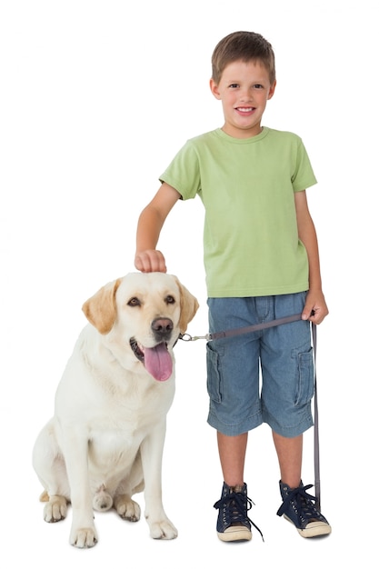 Mignon petit garçon debout avec son chien labrador souriant à la caméra