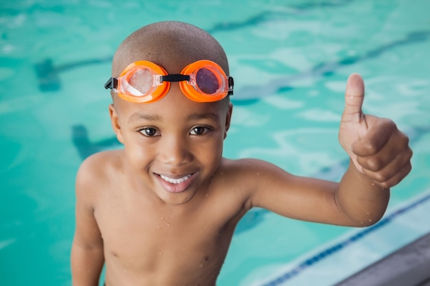 Mignon petit garçon donnant les pouces vers le haut à la piscine