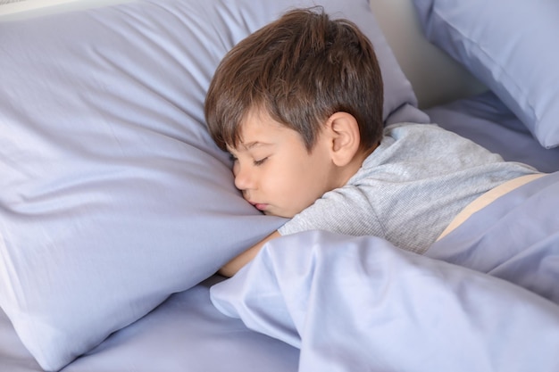 Mignon petit garçon dormant dans son lit à la maison