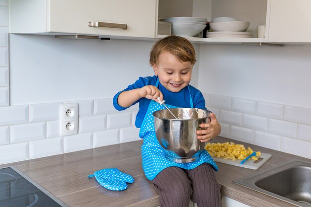 Mignon petit garçon drôle de cuisson du gâteau aux pommes dans la cuisine domestique