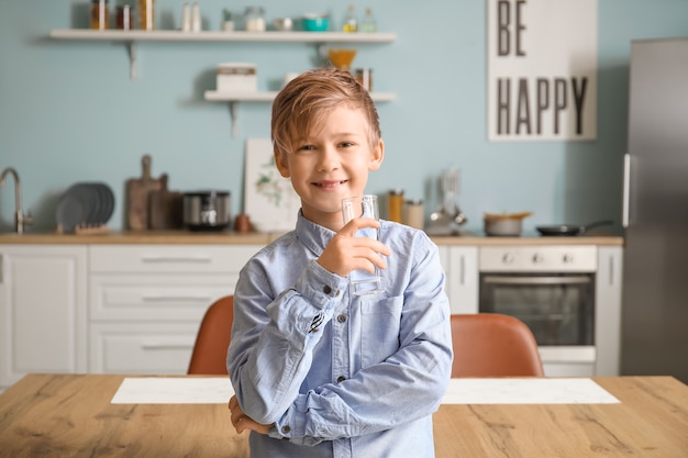 Mignon petit garçon eau potable dans la cuisine